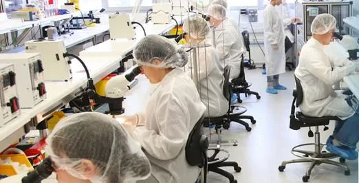 Creganna Medical's cleanroom production floor — technicians in cleanroom garb working at microscope stations, the controlled environment this energy monitoring had to work within.