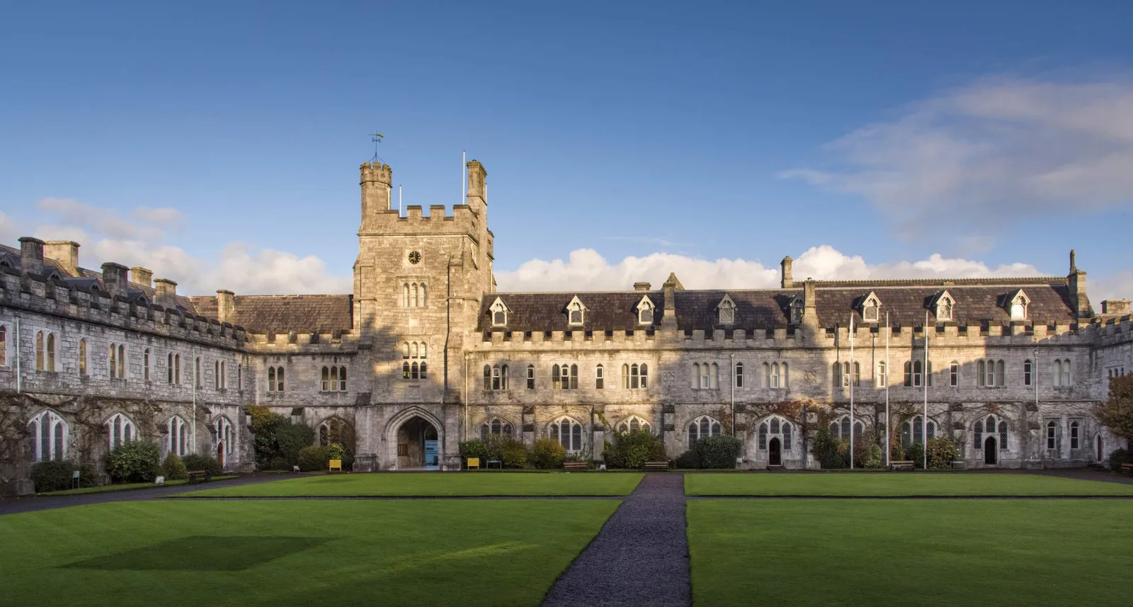 University College Cork's historic Quadrangle building, with its landmark clock tower, viewed across the lawn.