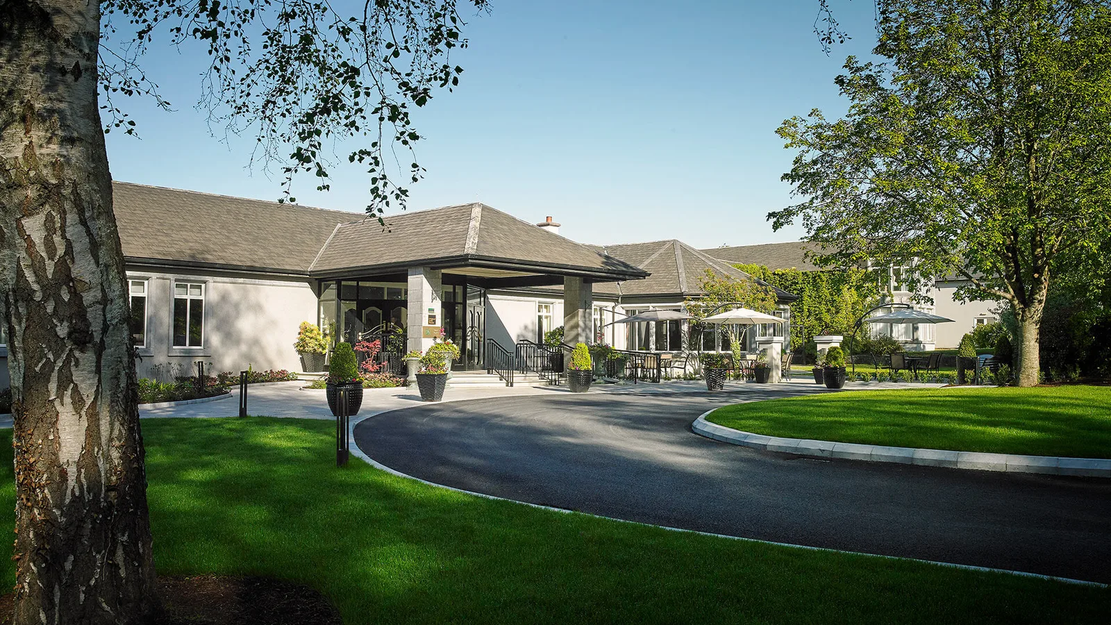 Woodlands Hotel's main entrance and front driveway, a single-storey hotel building surrounded by landscaped gardens.